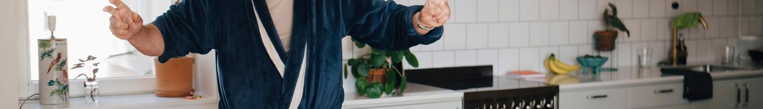 man i morgonrock dansar i köket