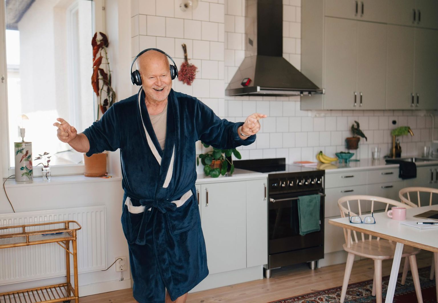 man i morgonrock dansar i köket