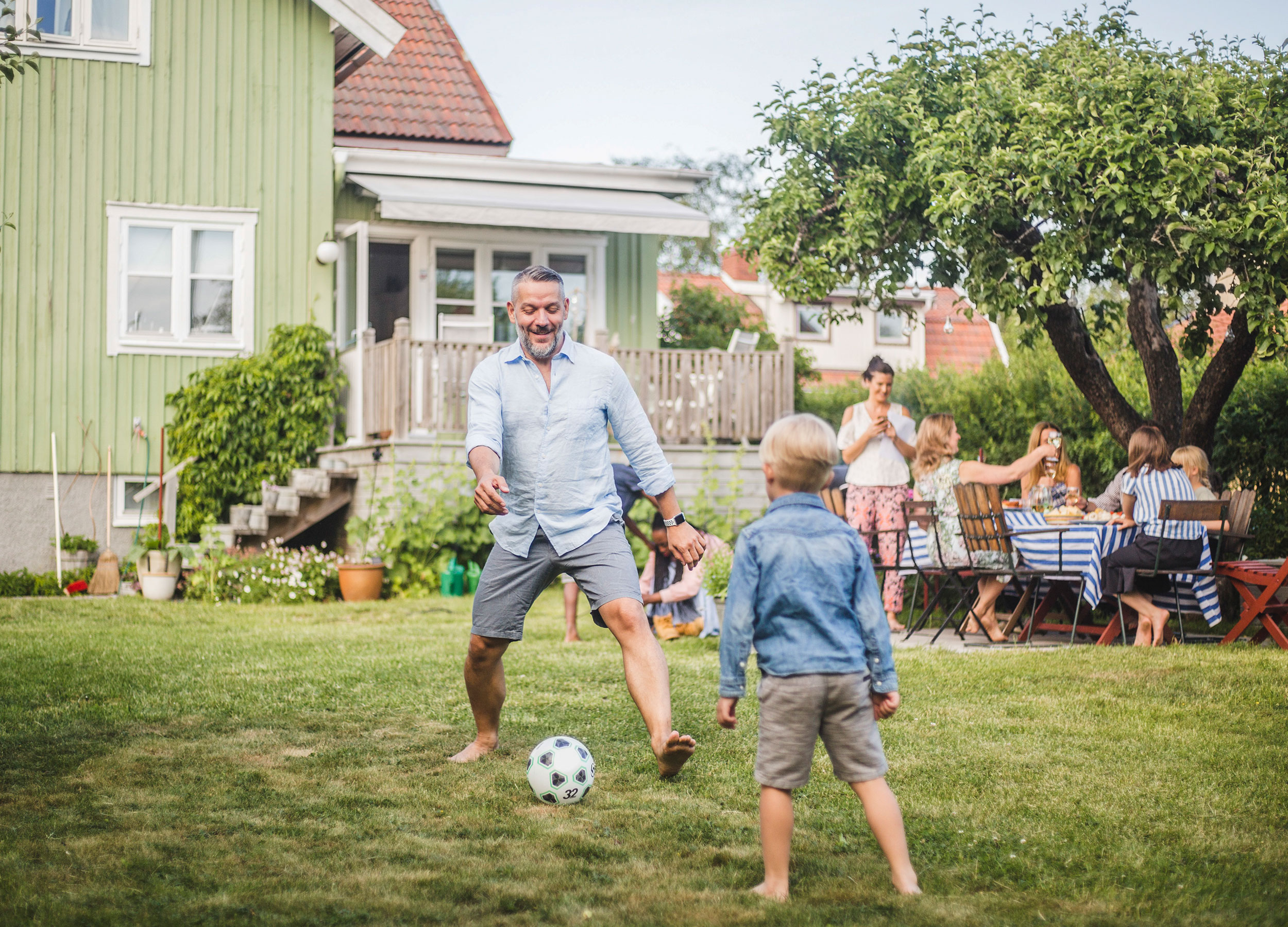 man och pojke spelar fotboll utanför villa