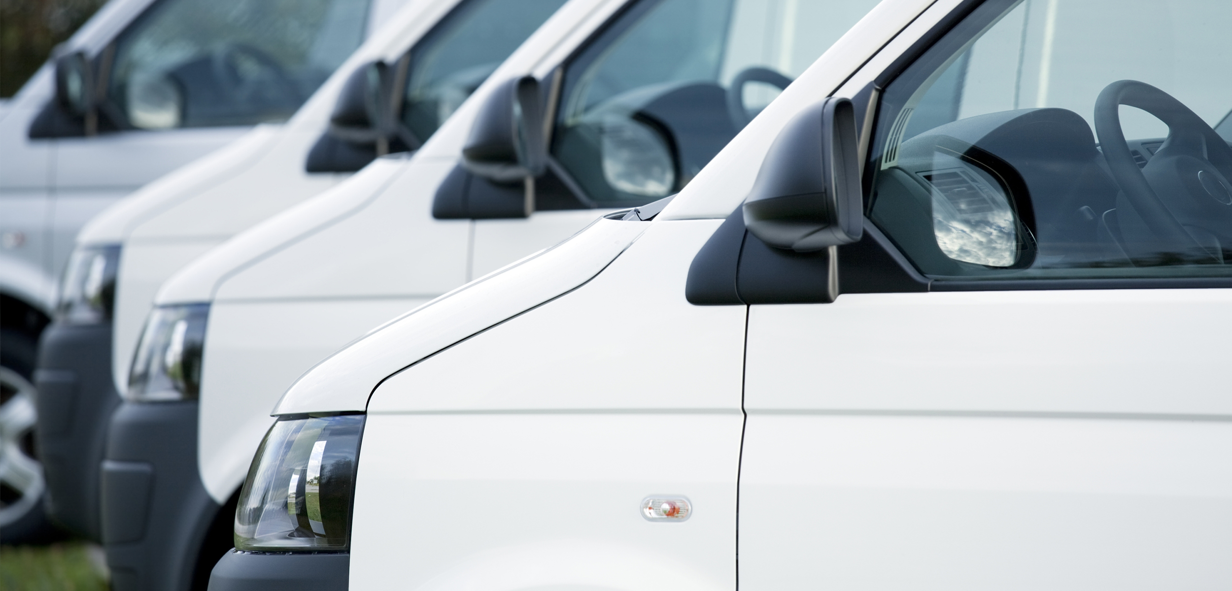 flera vita små lastbilar parkerade på rad