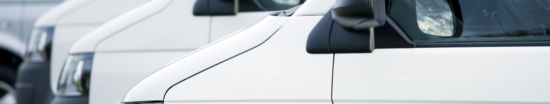 flera vita små lastbilar parkerade på rad