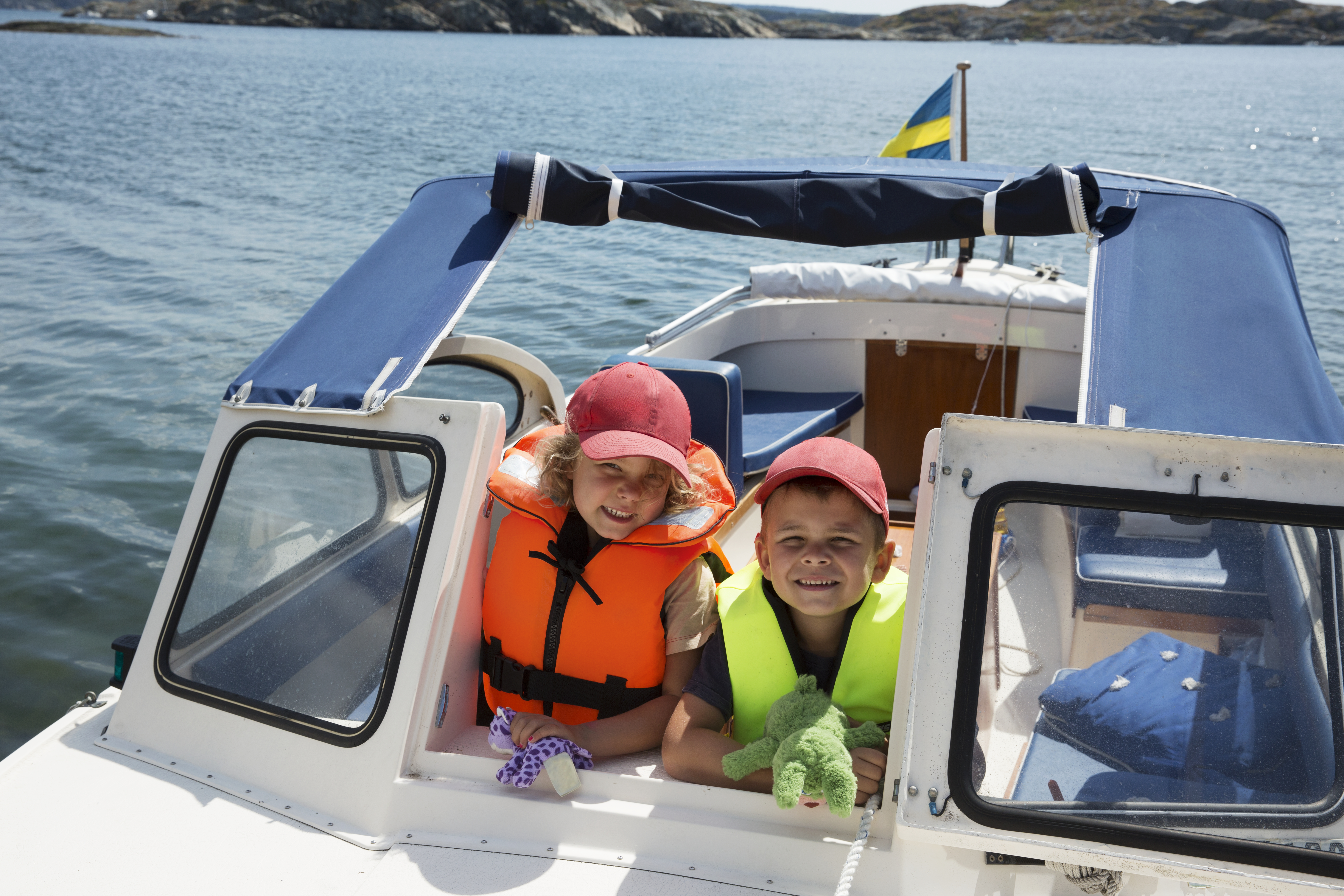 Två barn med flytväst i en motorbåt