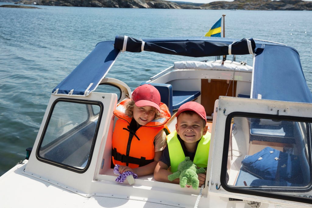 Två barn med flytväst i en motorbåt