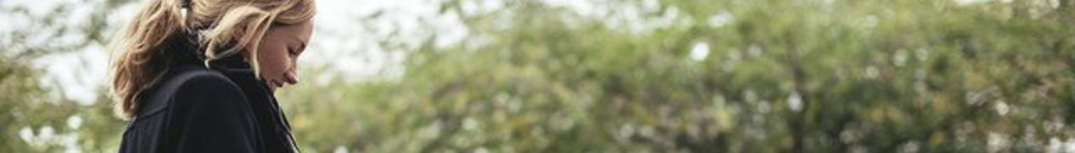 Kvinna tittar på sin telefon bredvid sin parkerade bil