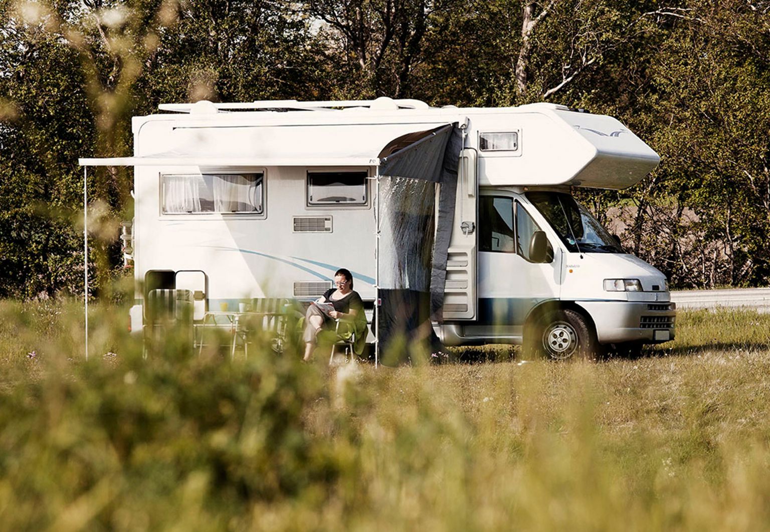 kvinna sitter i solen utanför sin husbil