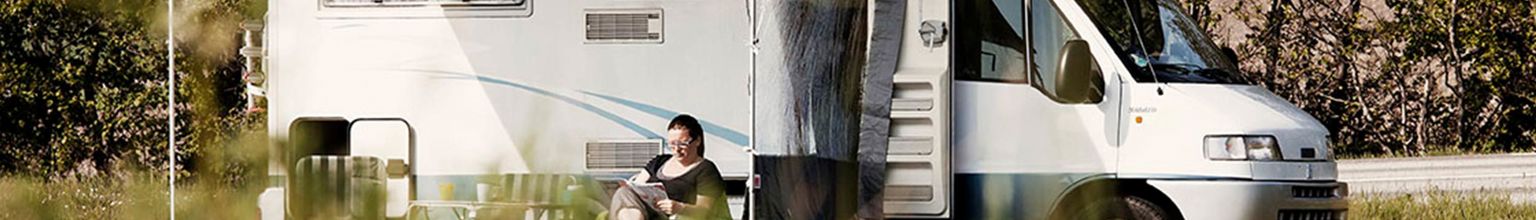 kvinna sitter i solen utanför sin husbil
