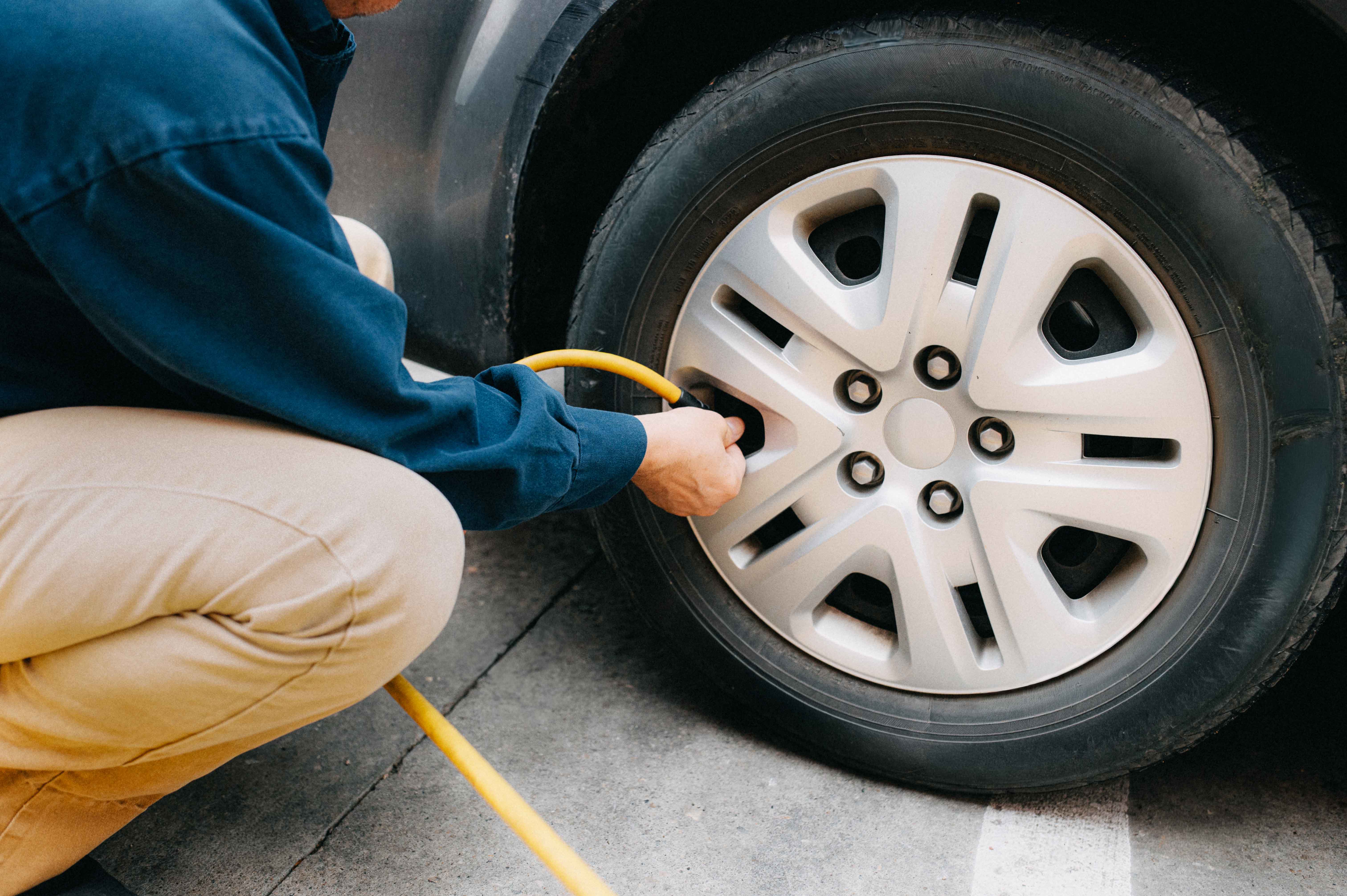 En man fyller på luft i sitt bildäck med en slang
