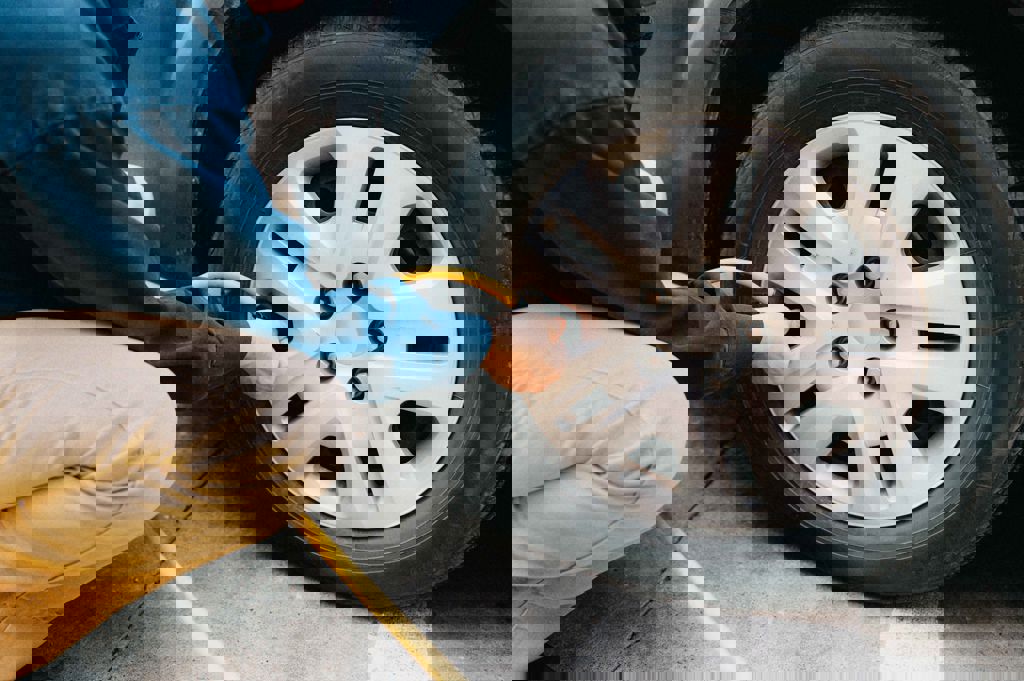 En man fyller på luft i sitt bildäck med en slang