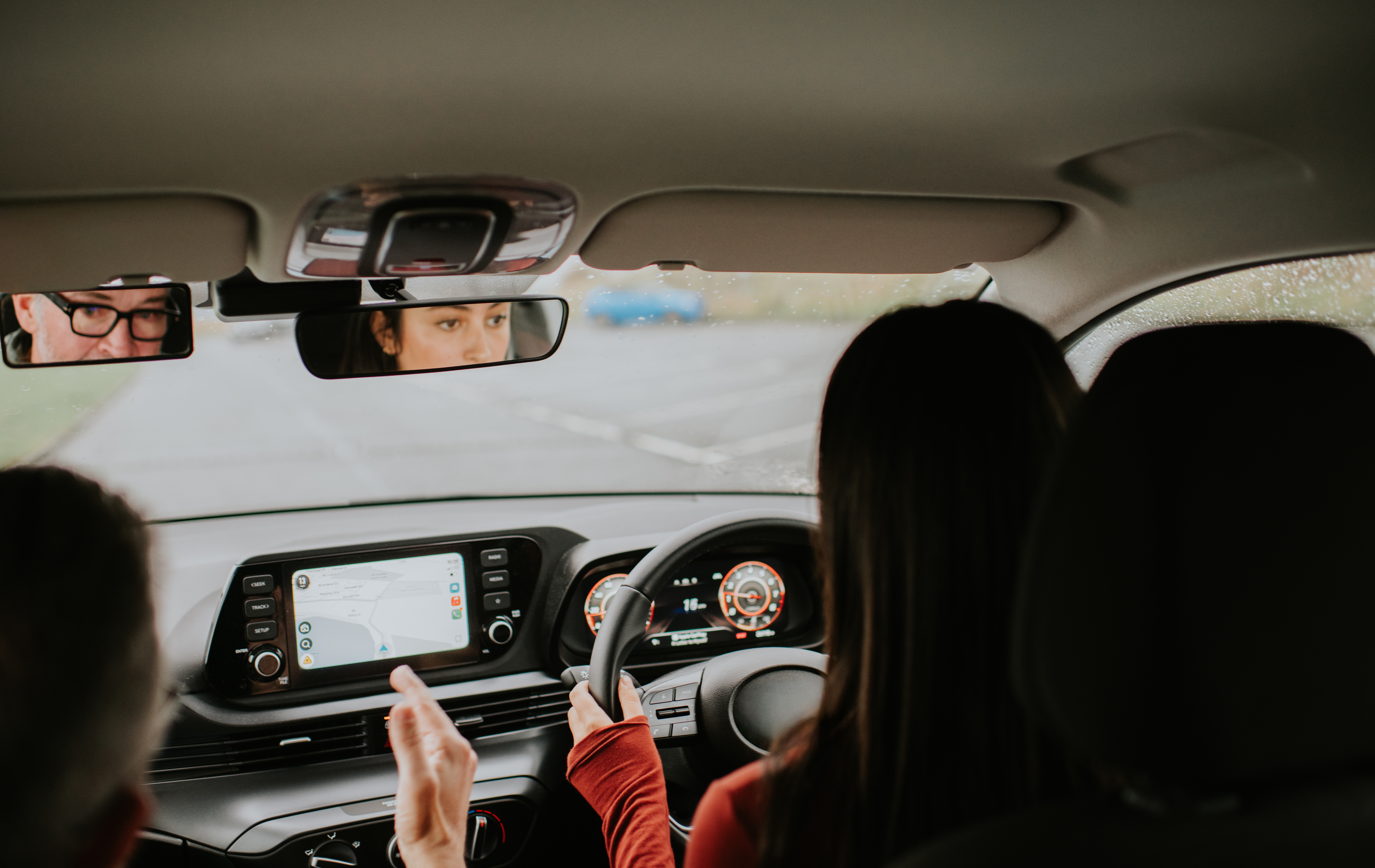Ung kvinna sitter vid ratten och bredvid sig har hon en äldre man