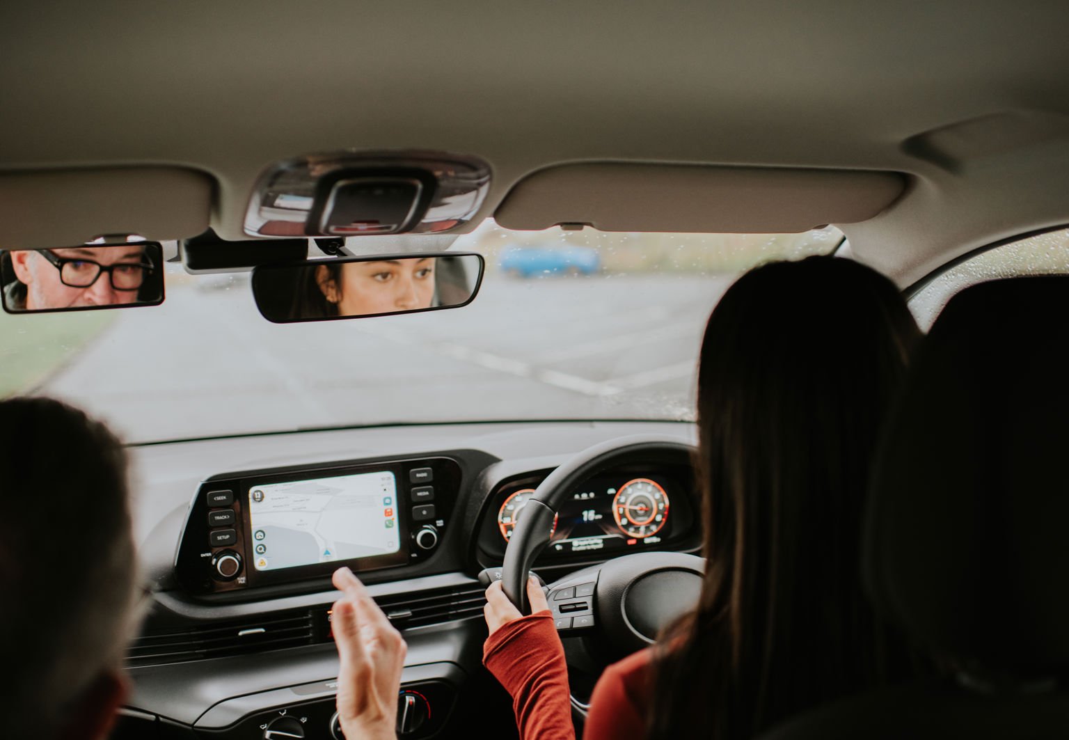 Ung kvinna sitter vid ratten och bredvid sig har hon en äldre man