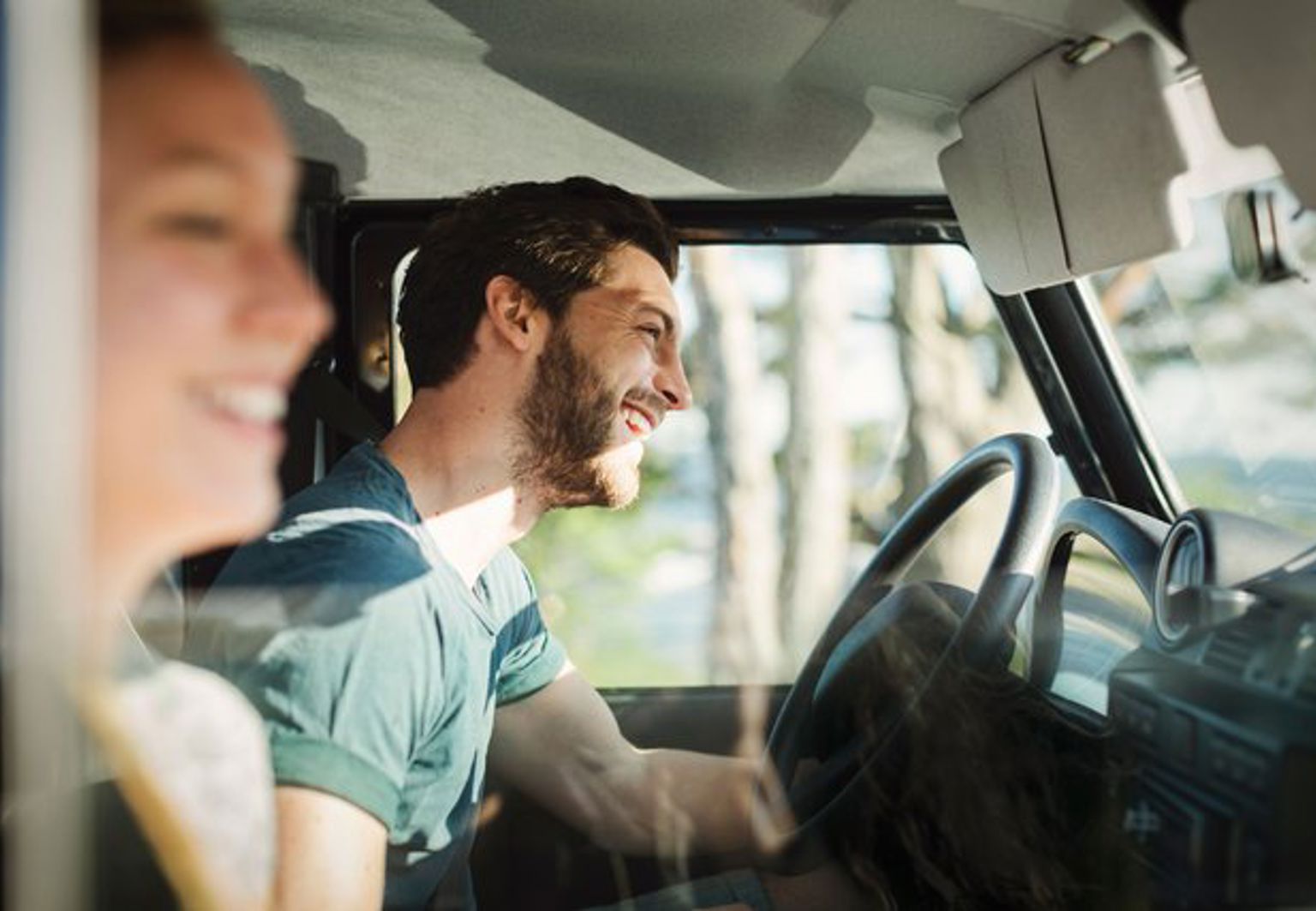 Man och kvinna sitter i en bil och är glada