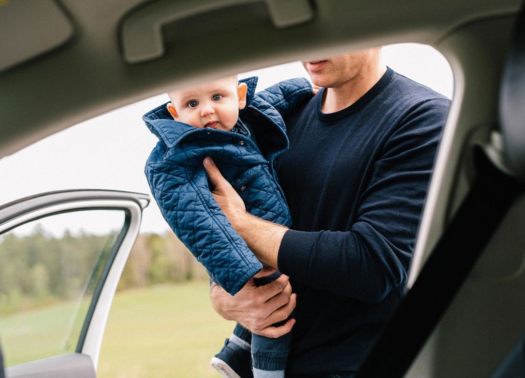 man sätter ett litet barn i bilen