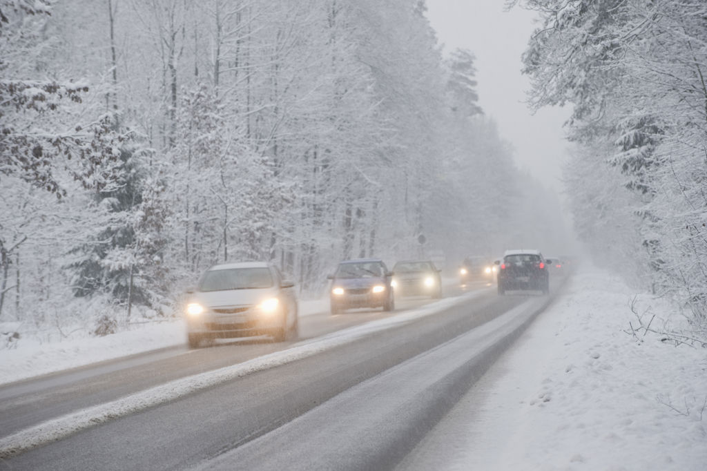Trafikerad landsväg i snöigt och dimmigt landskap