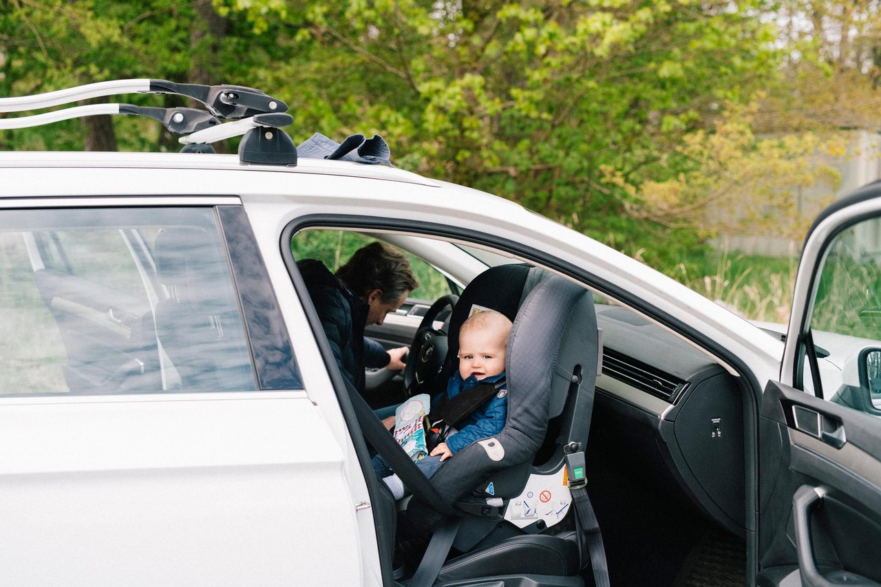 Bebis sitter bakåtvänd i en bilbarnstol i passagerarsätet fram