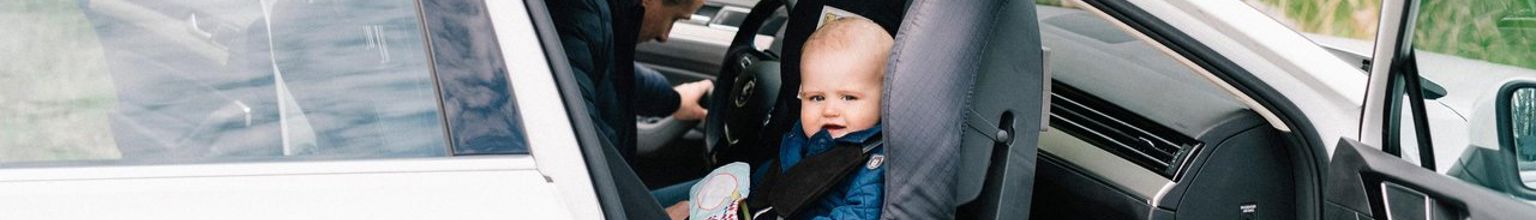 Bebis sitter bakåtvänd i en bilbarnstol i passagerarsätet fram