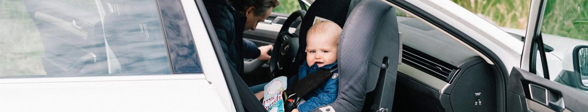 Bebis sitter bakåtvänd i en bilbarnstol i passagerarsätet fram