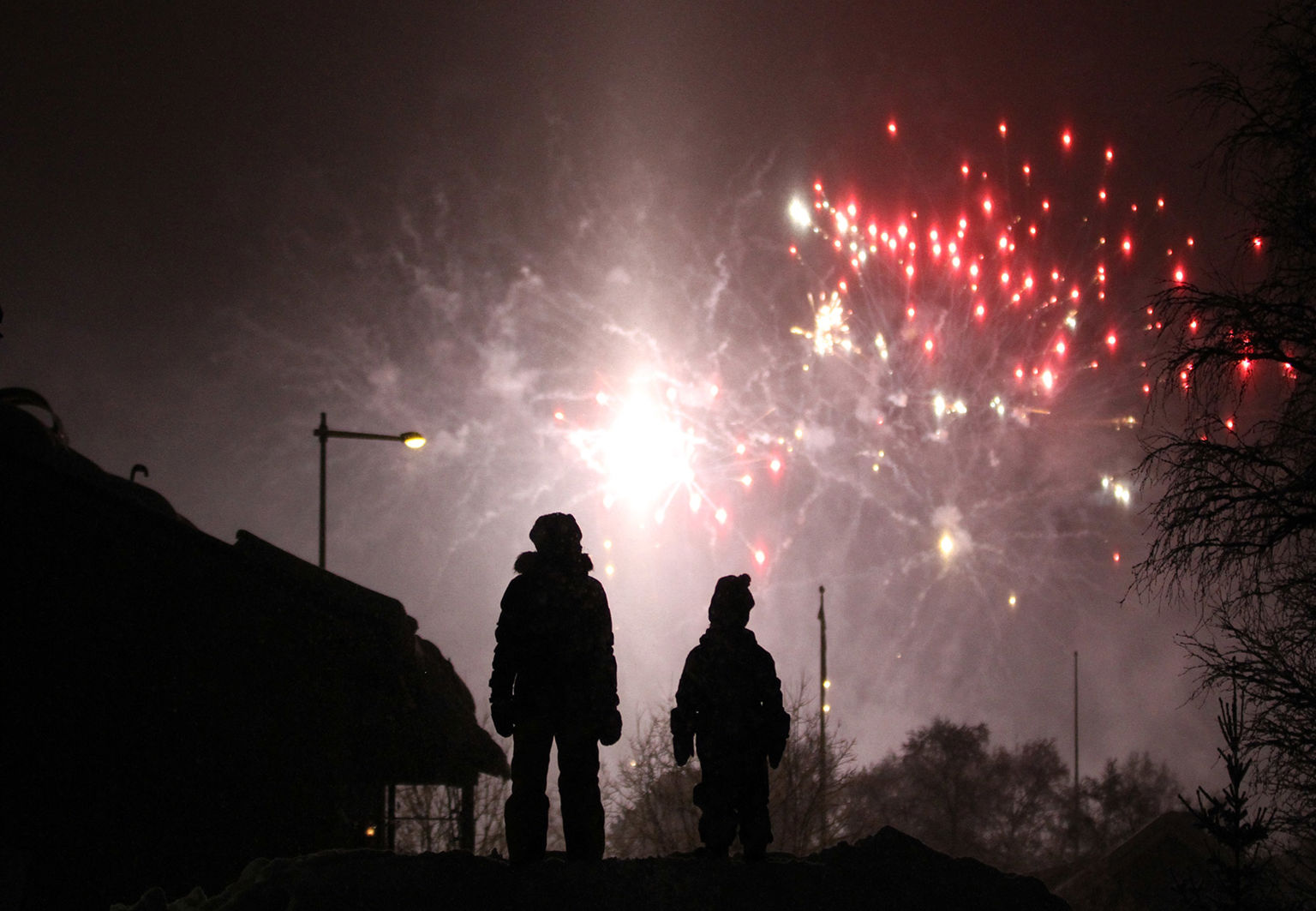 Barn är ute på kvällen och tittar upp på fyrverkerier