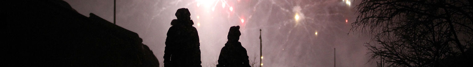 Barn är ute på kvällen och tittar upp på fyrverkerier