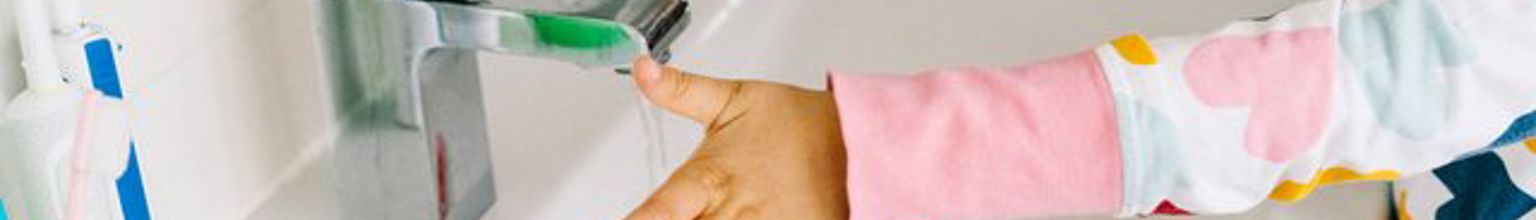 Flicka tvättar händerna i ett handfat