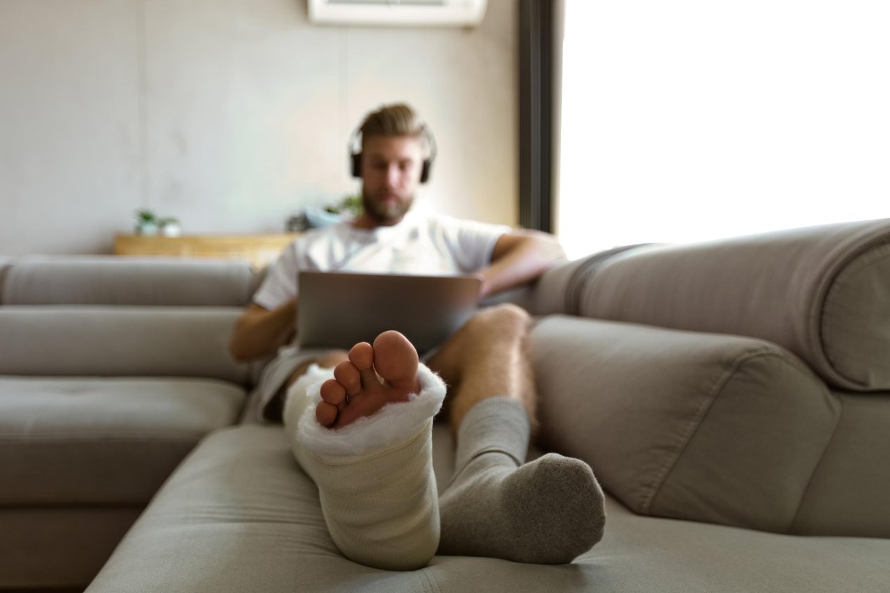 man med gips på benet ligger i soffa