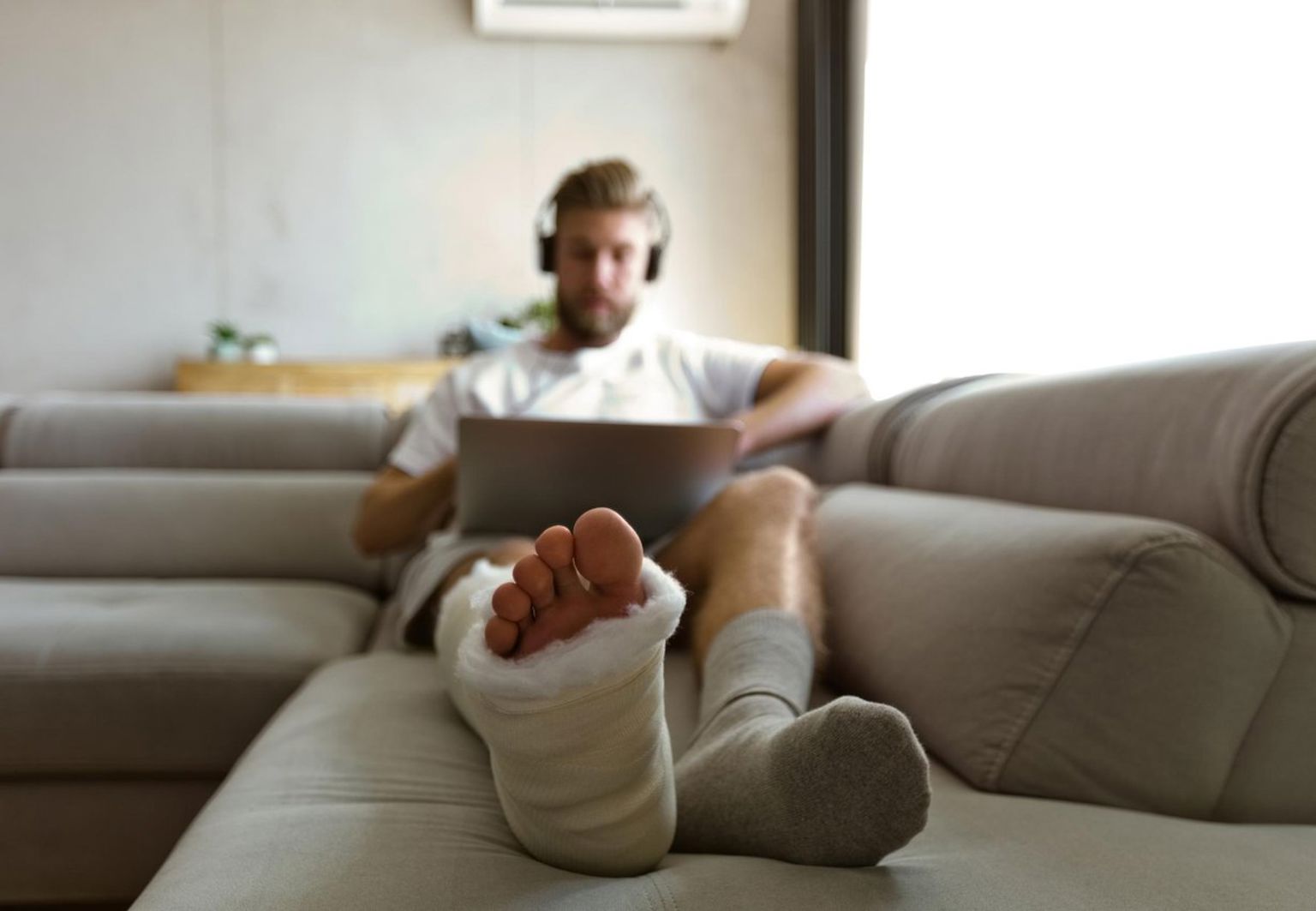 man med gips på benet ligger i soffa