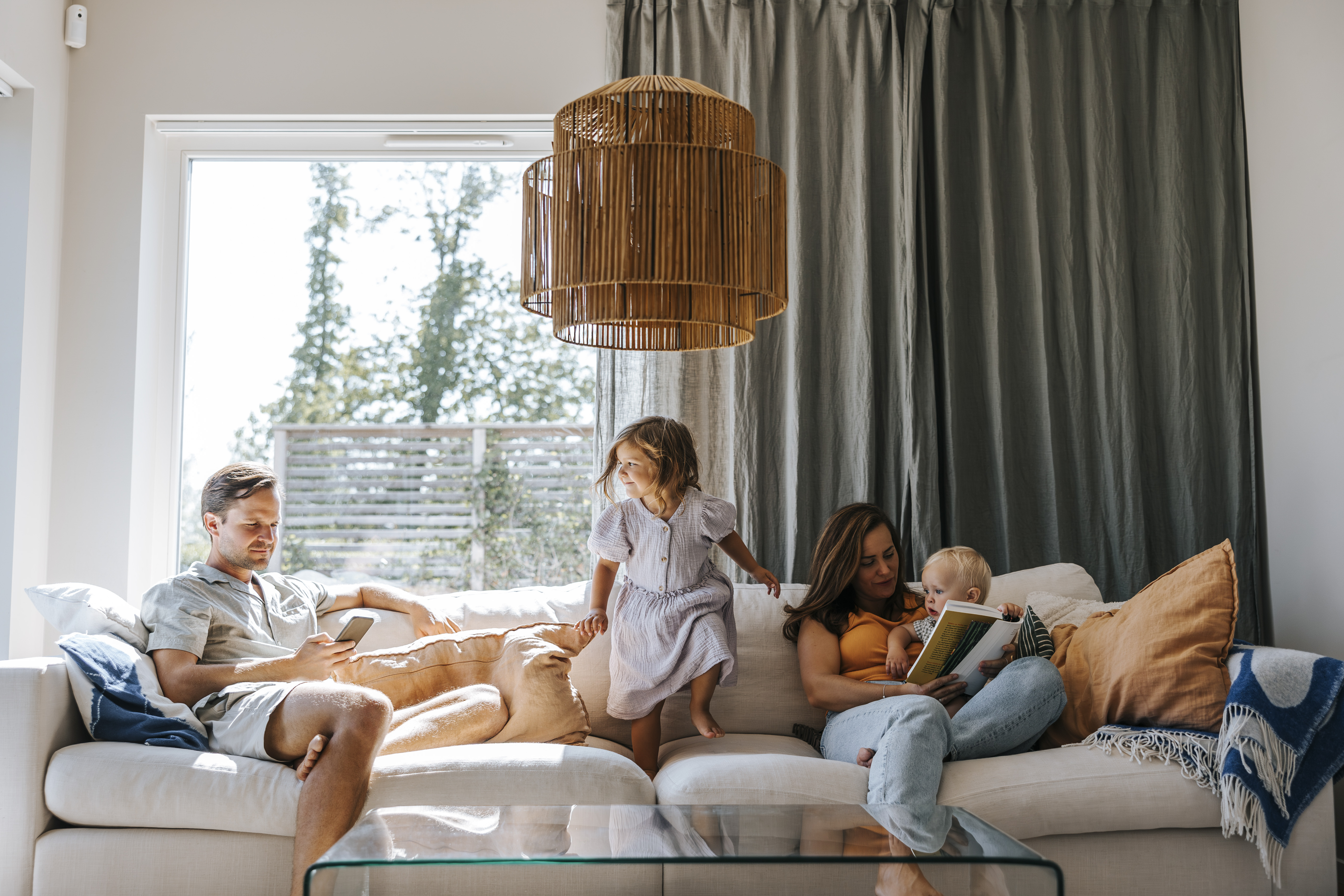 Mamma, pappa och barn umgås i soffa i vardagsrum