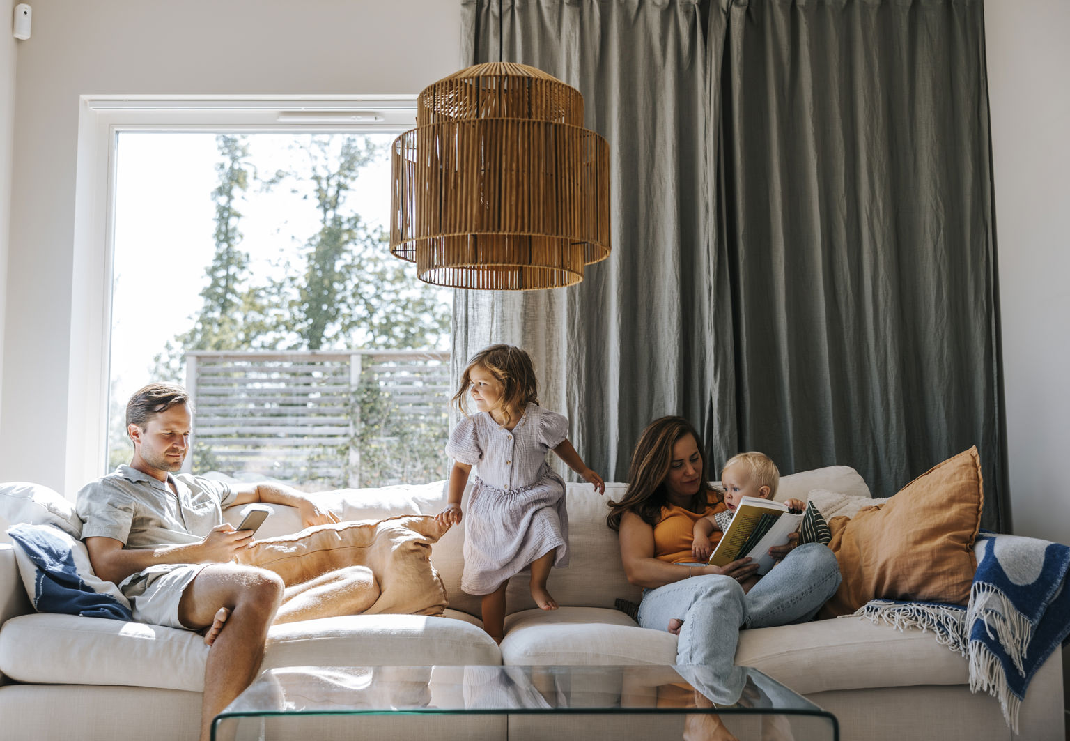 Mamma, pappa och barn umgås i soffa i vardagsrum