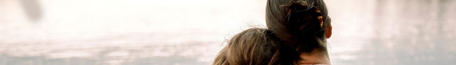 mamma håller om sin dotter vid en sjö