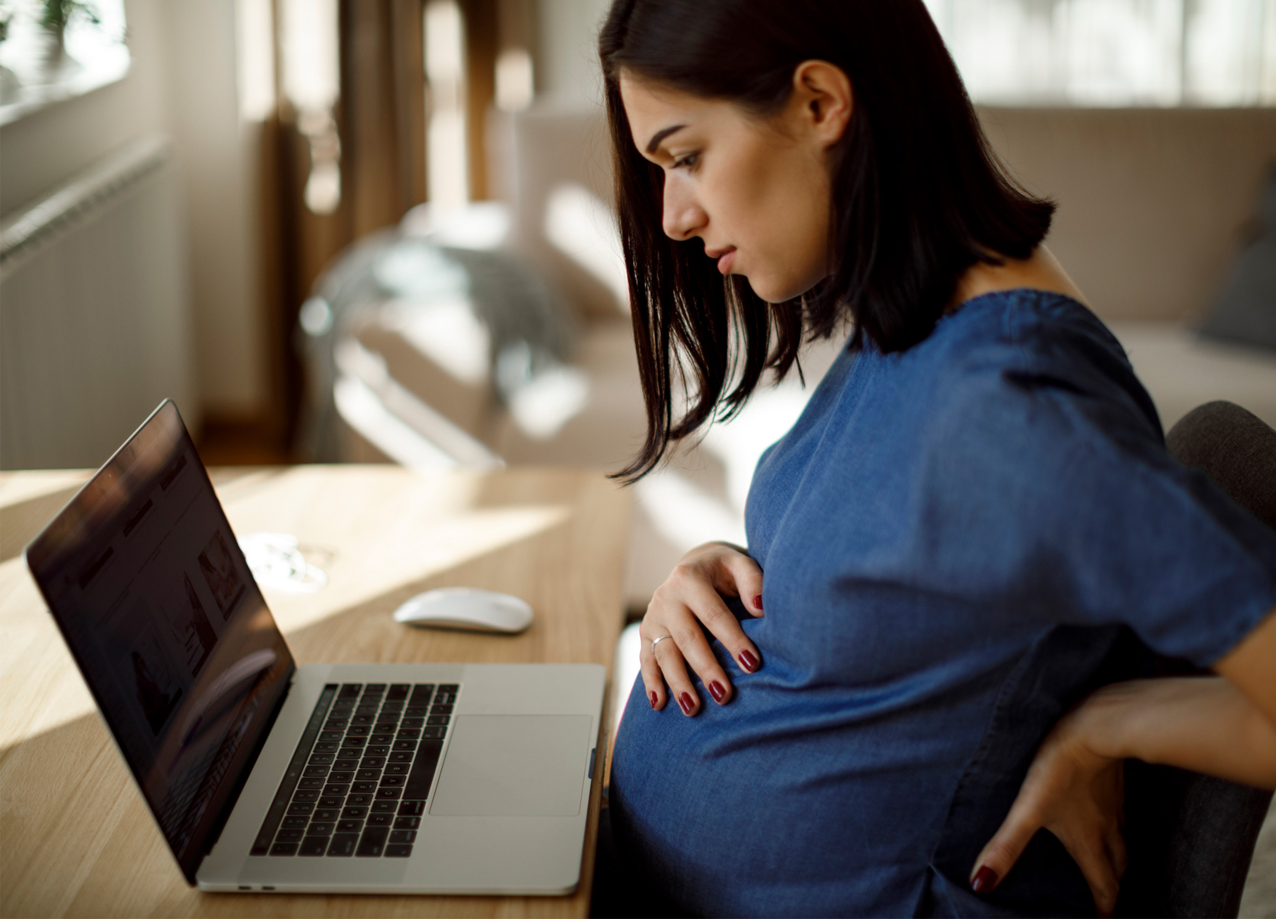 gravid kvinna sitter vid en laptop