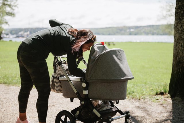 Kvinna är utomhus på våren med sin barnvagn