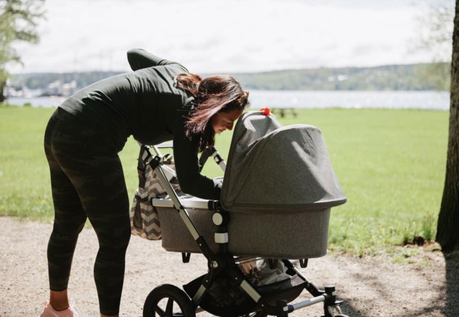 Kvinna är utomhus på våren med sin barnvagn