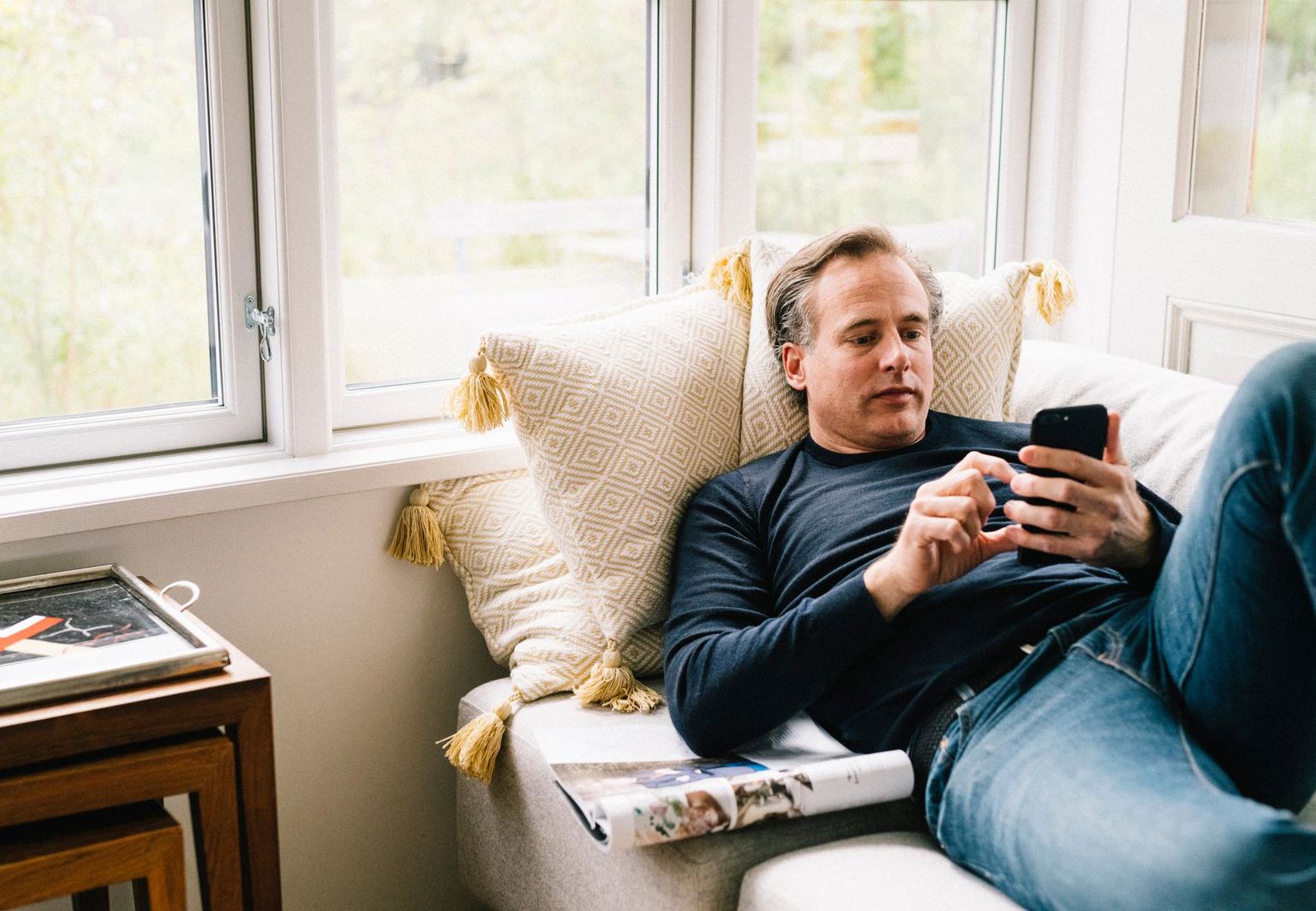 man ligger i soffan kollar på mobilen