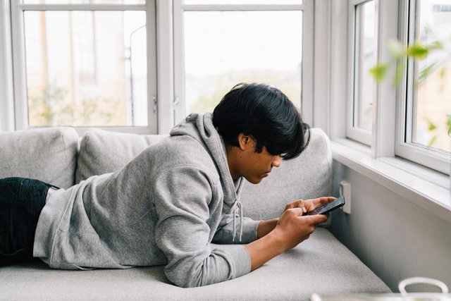 Tonåring surfar på sin telefon i soffan