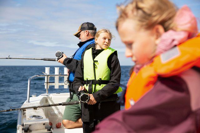 Barn och en vuxen fiskar från en båt