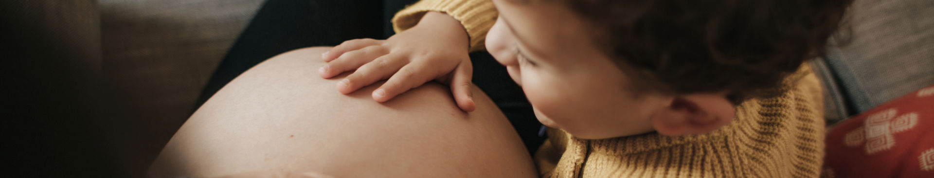 Pojke klappar på sin mammas gravida mage