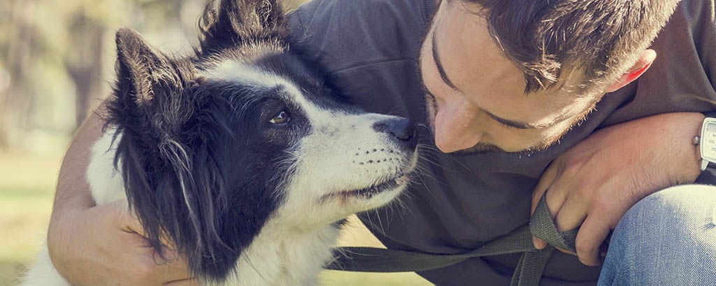 Husse håller om sin hund och har ögonkontakt