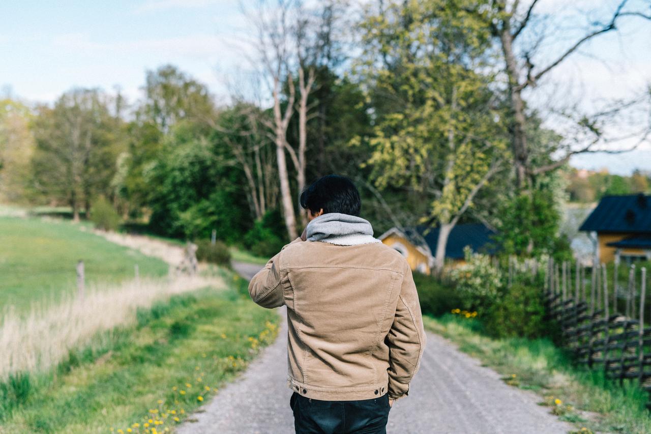 Tonårig pojke som går på grusstig i ett vårgrönt Sverige