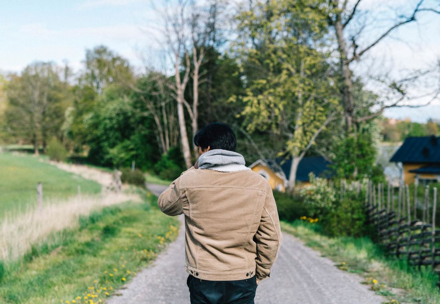 Tonårig pojke som går på grusstig i ett vårgrönt Sverige
