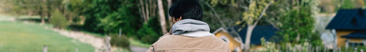 Tonårig pojke som går på grusstig i ett vårgrönt Sverige