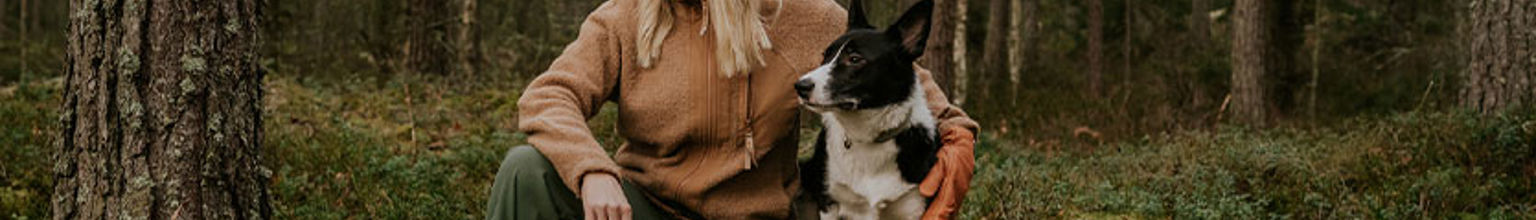 kvinna och border collie sitter på en sten i skogen