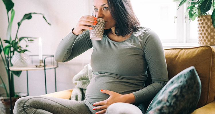 gravid kvinna dricker en kopp te