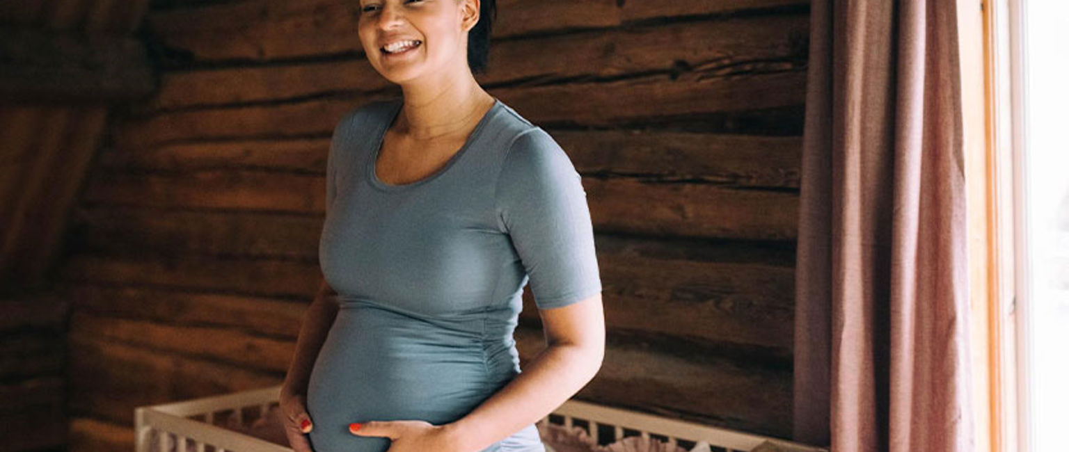 gravid kvinna framför en spjälsäng