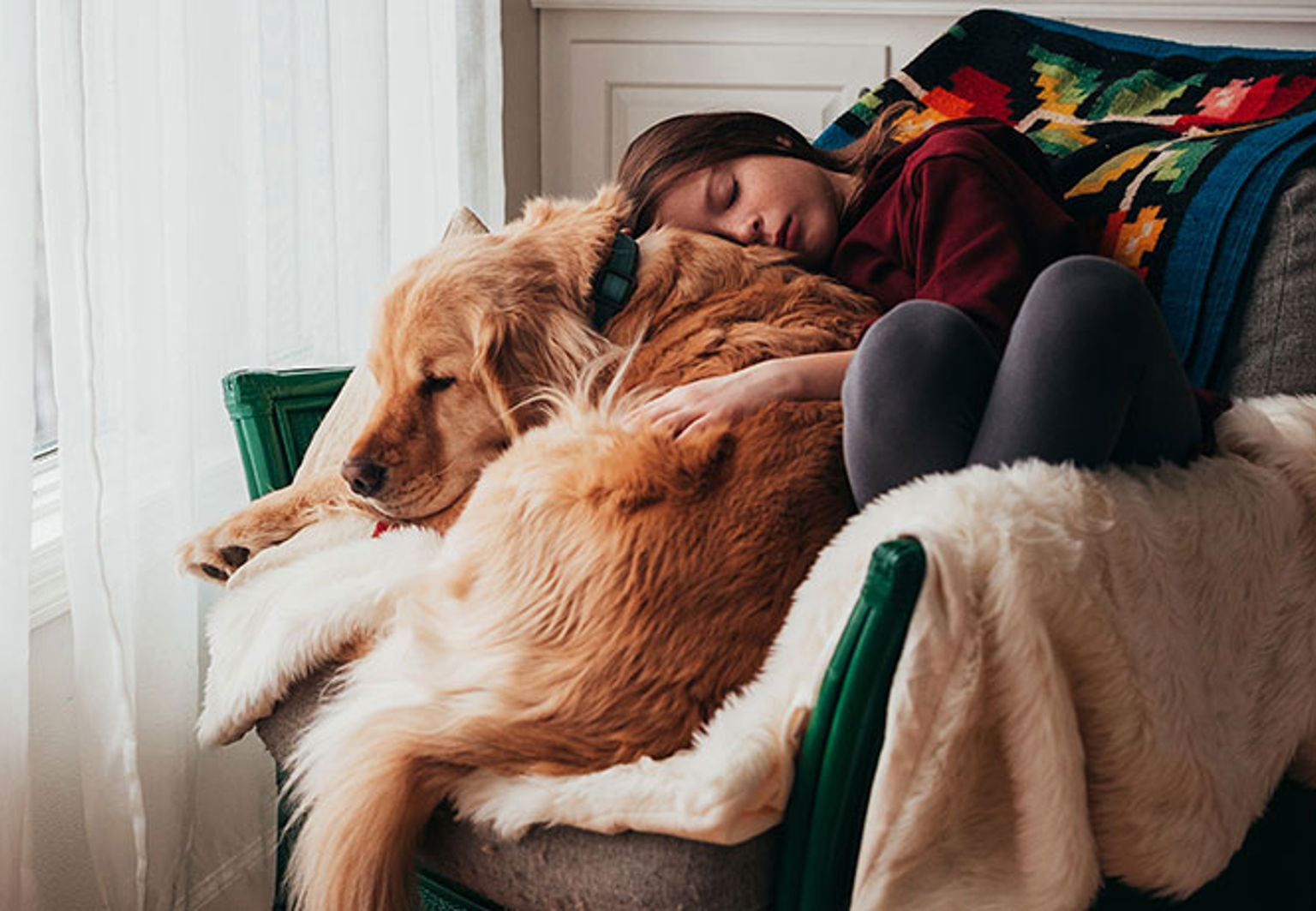 ung flicka vilar tillsammans med hund i en fåtölj