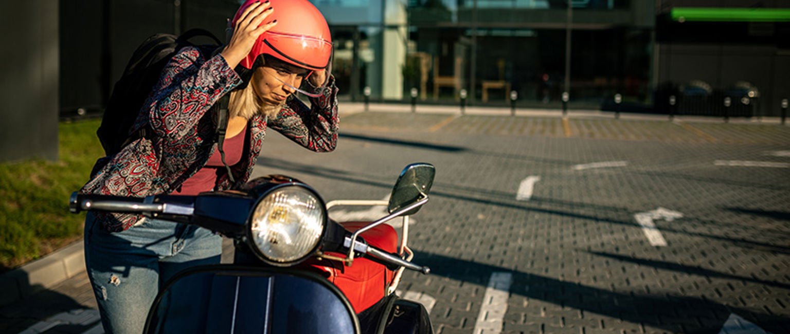 ung kvinna med röd hjälm vid sin moped
