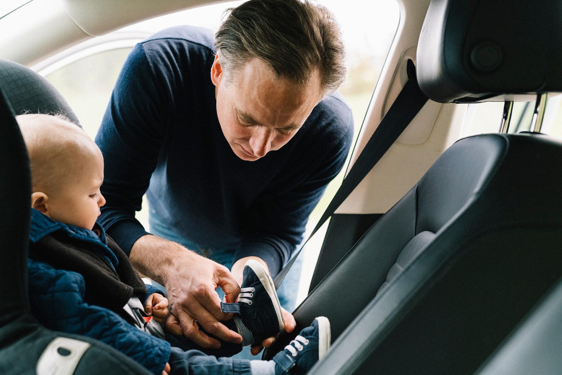 pappa spänner fast sitt barn i bilbarnstol