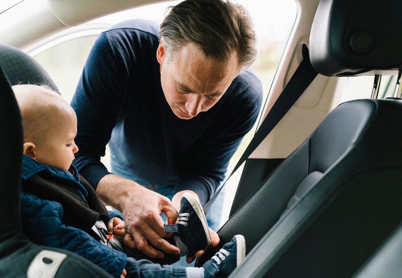 pappa spänner fast sitt barn i bilbarnstol