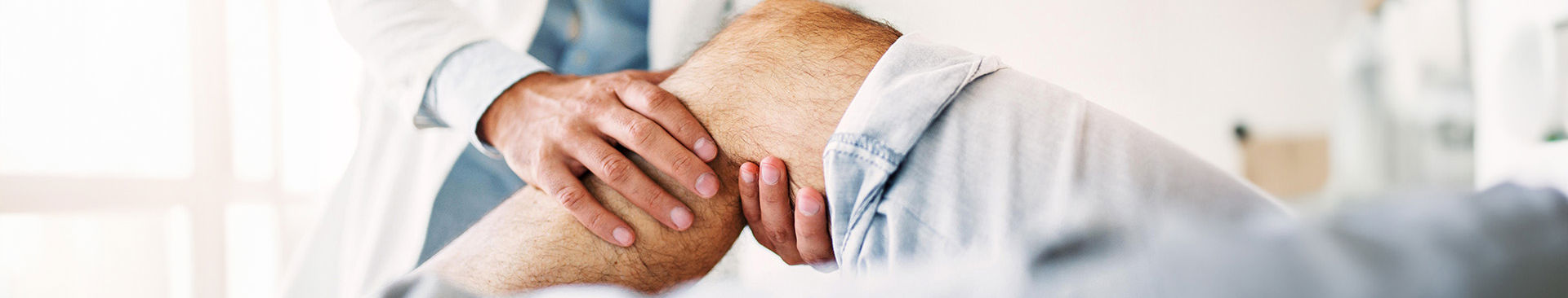 läkare undersöker knä på en patient