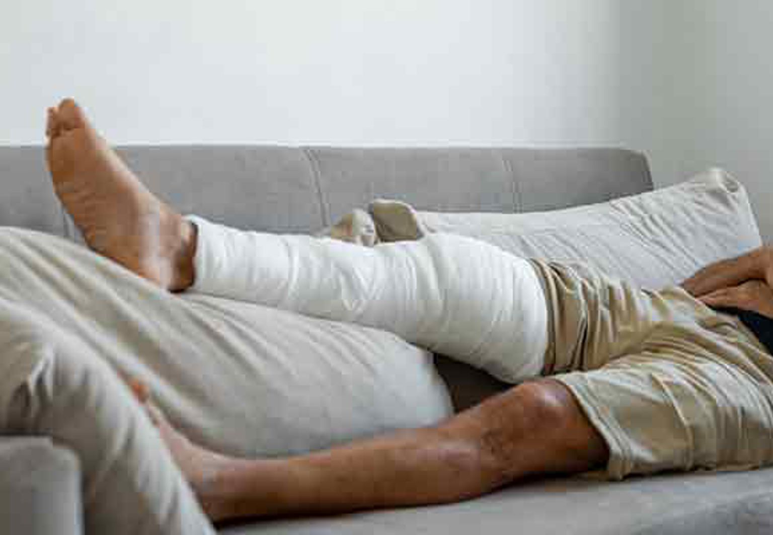 man med gipsat ben vilar på en soffa