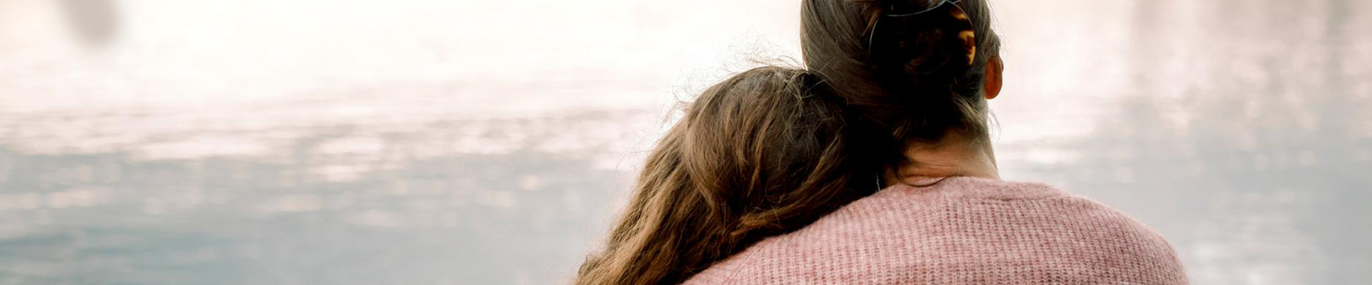 mamma håller om sin dotter vid en sjö