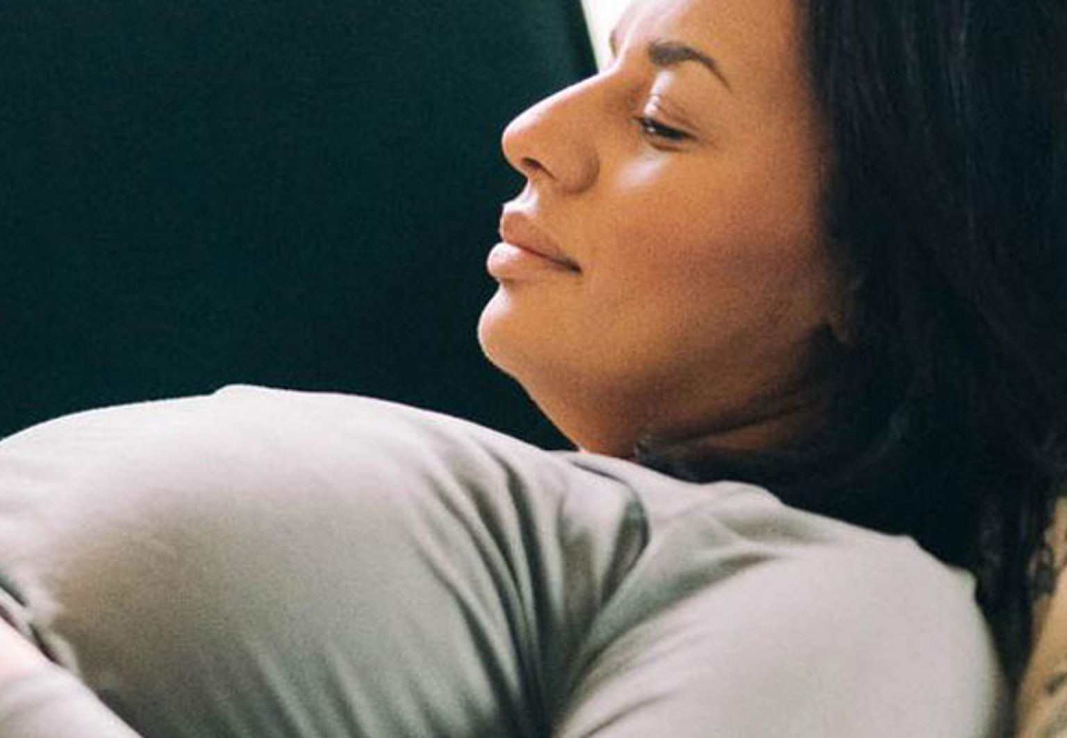 gravid kvinna ligger på soffa tittar på mobil